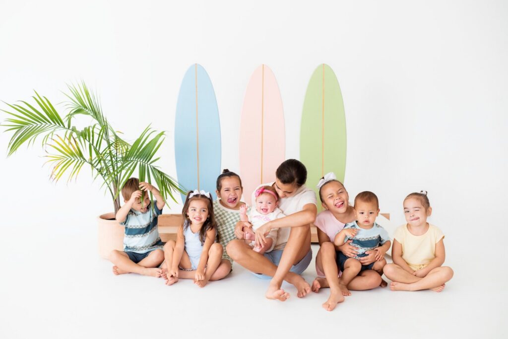 Cousins posing together on beach-inspired surfer set during summer photo session at Jacksonville natural light studio.