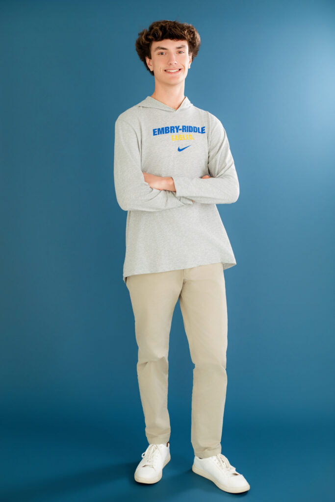 Simple clean standing high school graduate portrait featuring senior wearing Embry–Riddle Aeronautical University shirt during Jacksonville, FL studio graduation session.