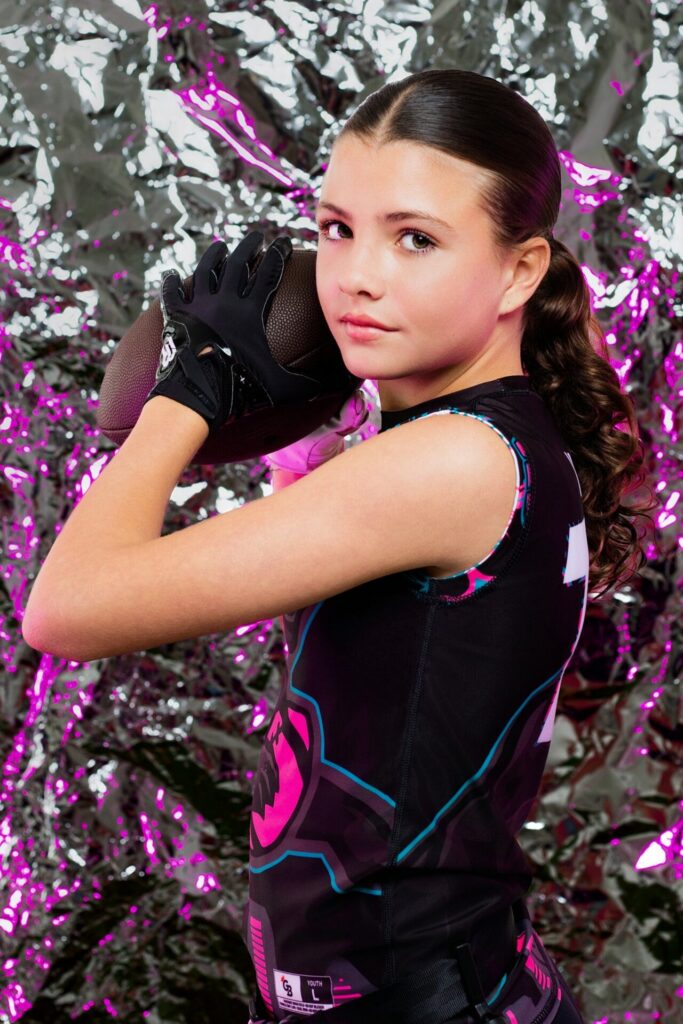 Football athlete portrait at Jacksonville photo studio featuring dramatic foil and colored lights background during indoor sports media day photography session.