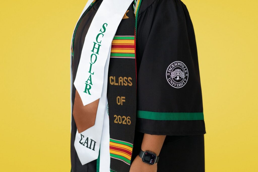 Jacksonville university senior class of 2026 graduation portrait featuring graduates gown and honor cords during colorful studio session in Florida.