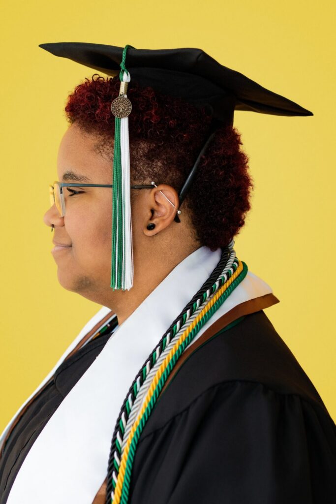 Jacksonville university senior graduation portrait featuring graduate in cap, tassel, and honor cords during colorful studio session in Florida.