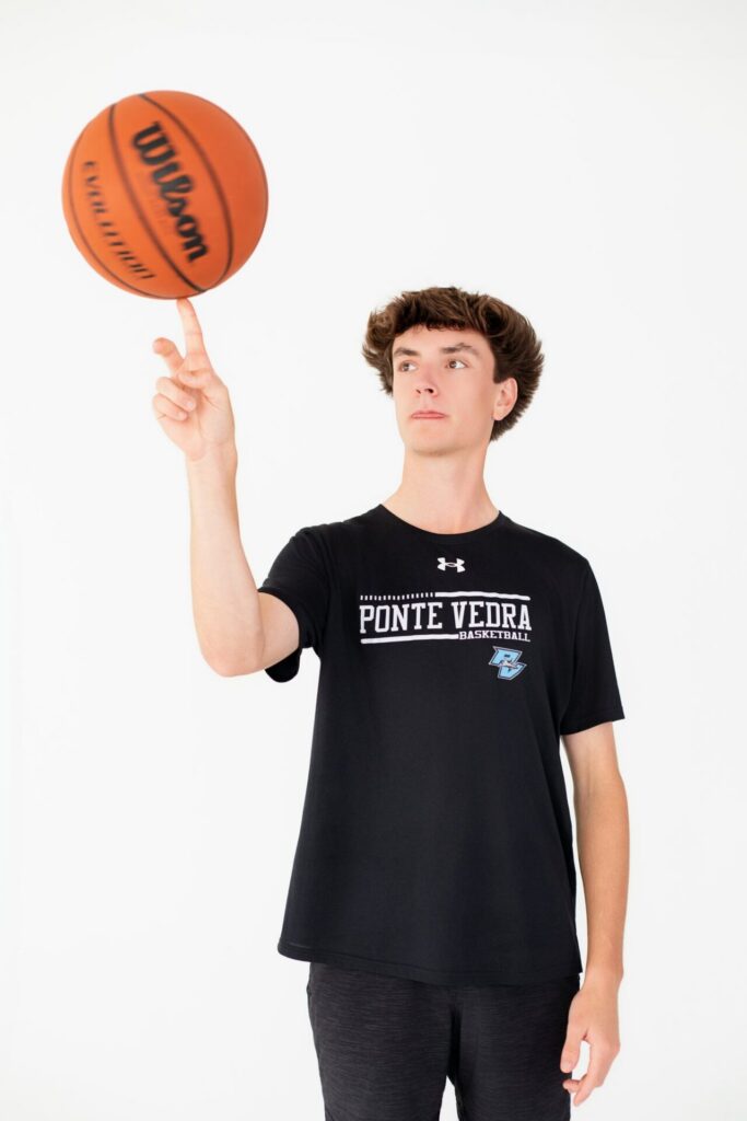 Ponte Vedra, FL basketball senior portrait featuring high school student athlete spinning basketball on finger during studio graduation session.