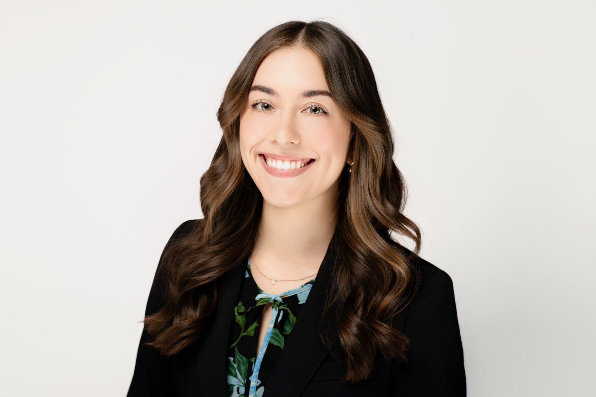 Professional headshot of a young woman in a suit and blouse against a light background