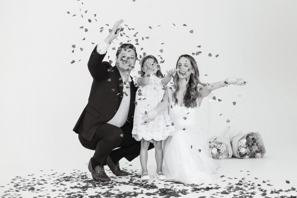 Black and white photo of family celebrating gender reveal using confetti and flowers, located in a Jacksonville photo studio