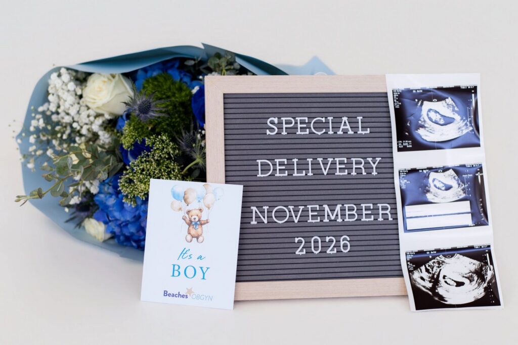 Boy gender reveal flat lay including blue flower bouquet, "it's a boy" card, special delivery sign, and ultrasound in Jacksonville, FL photo studio.