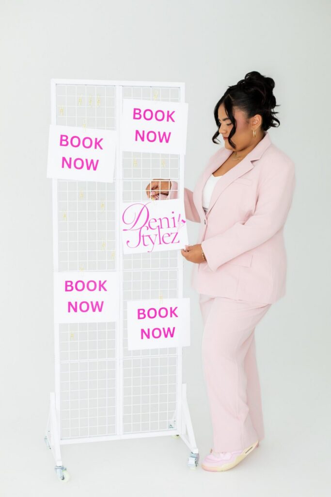 Deni of Deni Stylez Hair hanging up book now and logo papers to promote her hair styling business during a branding session at Jax Mini Sessions Studio