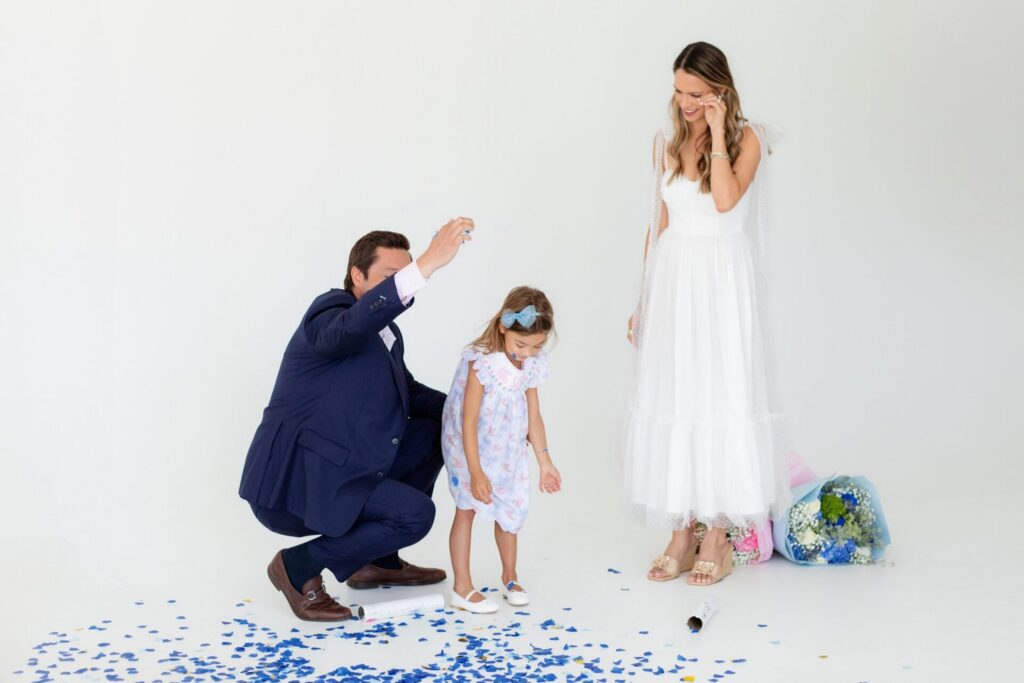 Mom wipes away happy tears during a Jacksonville gender reveal photo session as blue confetti fills the studio and family celebrates their baby boy.